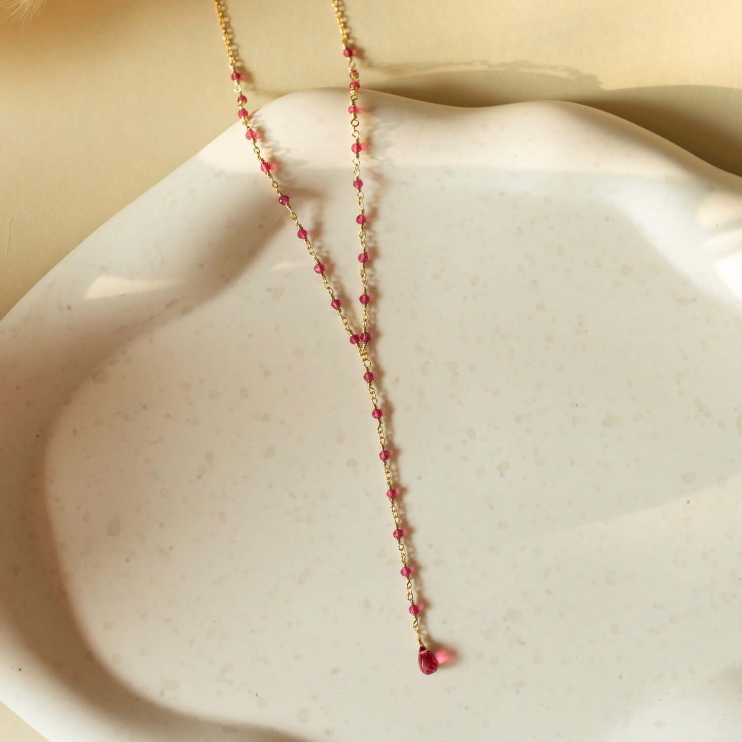 A pink necklace with tourmaline quartz laid on a clay plate.