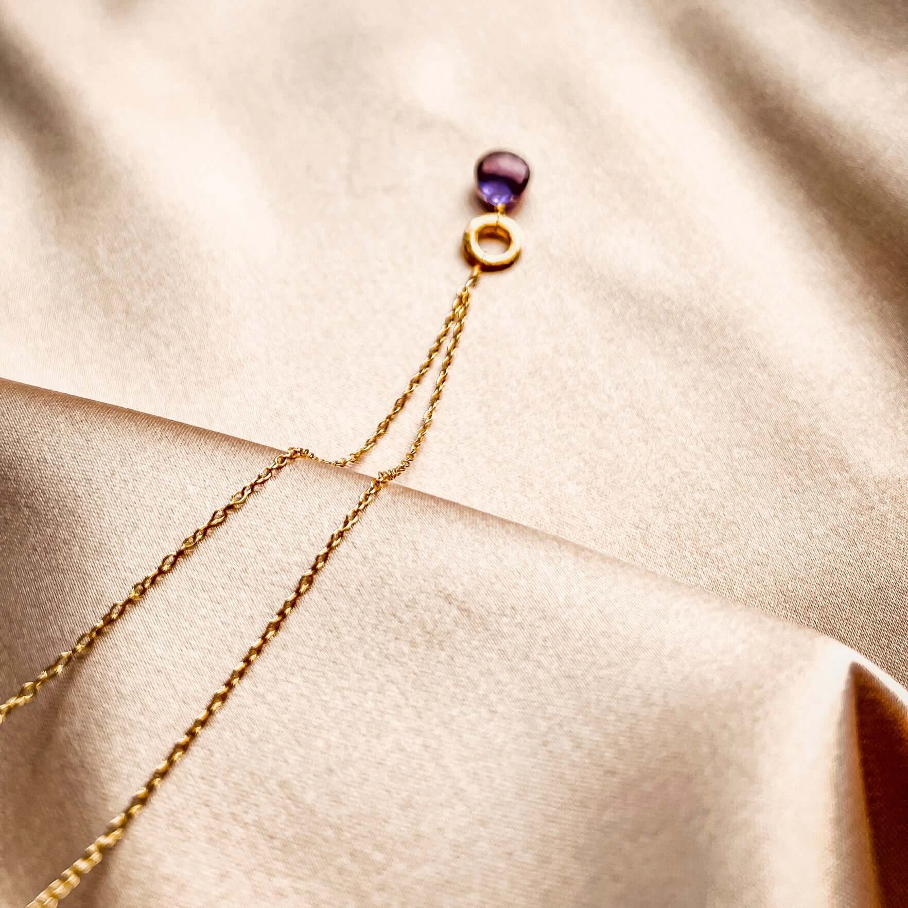 Layering chain with timeless amethyst gemstone. 14k gold plated .925 Italian silver, 16" length (extendable to 18"). Each stone unique, laid on a satin pink cloth.