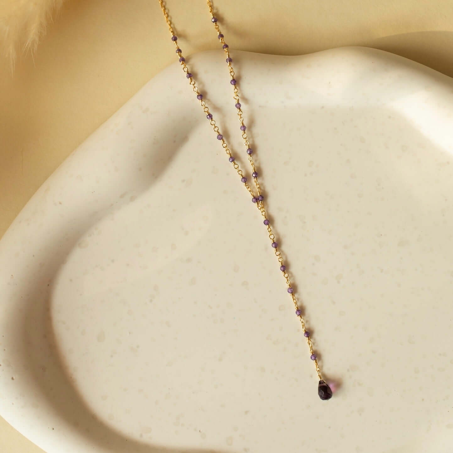 An amethyst necklace casually laid on a clay plate, showcasing handmade simplicity.