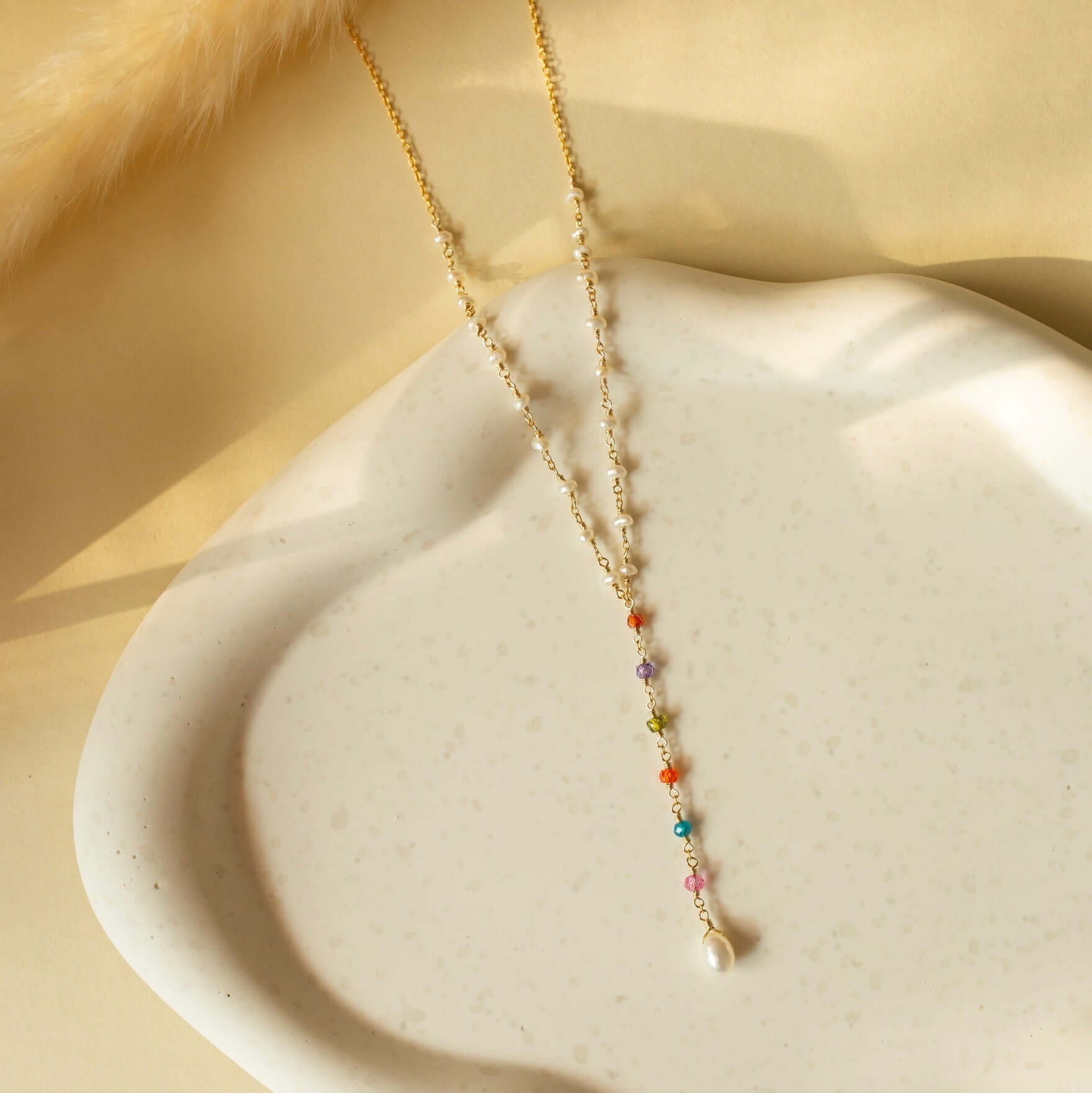 Delightful necklace with rainbow pearls on a clay plate.