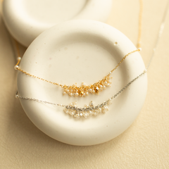 A delicate gold and silver beaded necklace with pearls on a white stone surface