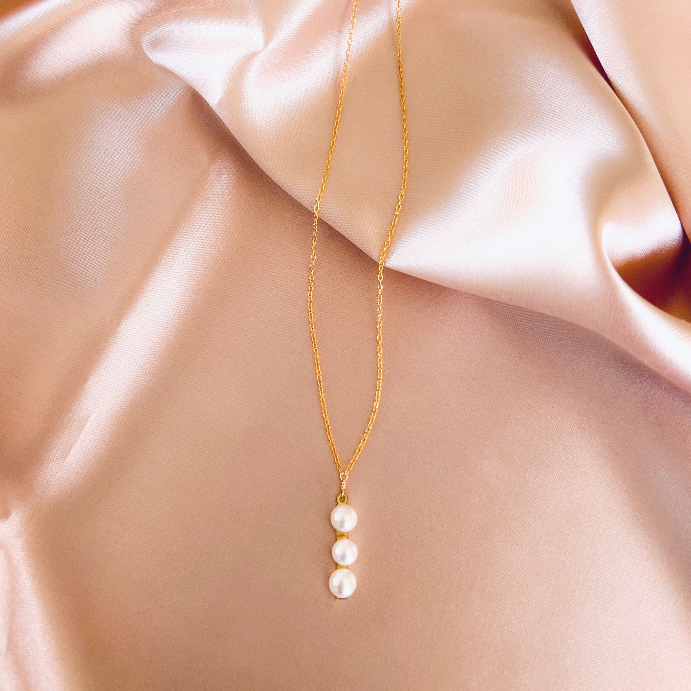 Necklace featuring three freshwater pearls on a slim gold bar, attached to a delicate 14k gold-plated chain