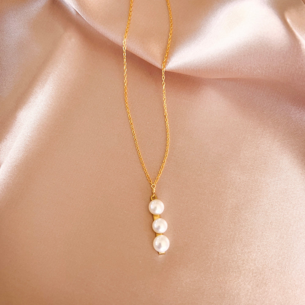 Necklace featuring three freshwater pearls on a slim gold bar, attached to a delicate 14k gold-plated chain