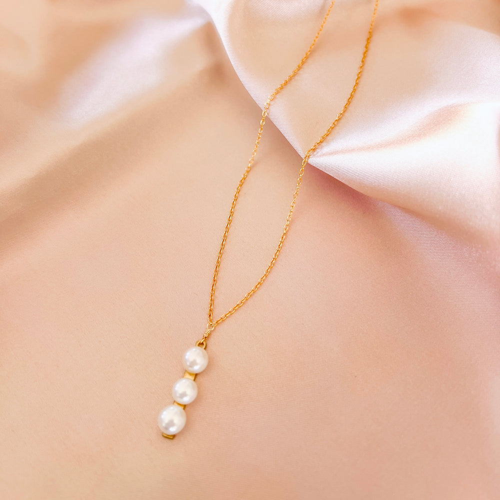 Necklace featuring three freshwater pearls on a slim gold bar, attached to a delicate 14k gold-plated chain
